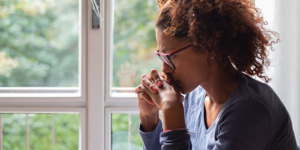 Lonely black woman near window thinking about something